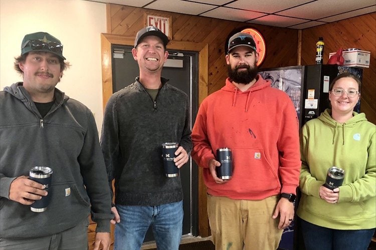 Photo of second place winners holding their prizes from the clay shoot. 