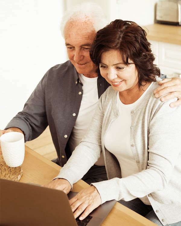 Photo of older couple looking at computer screen together.