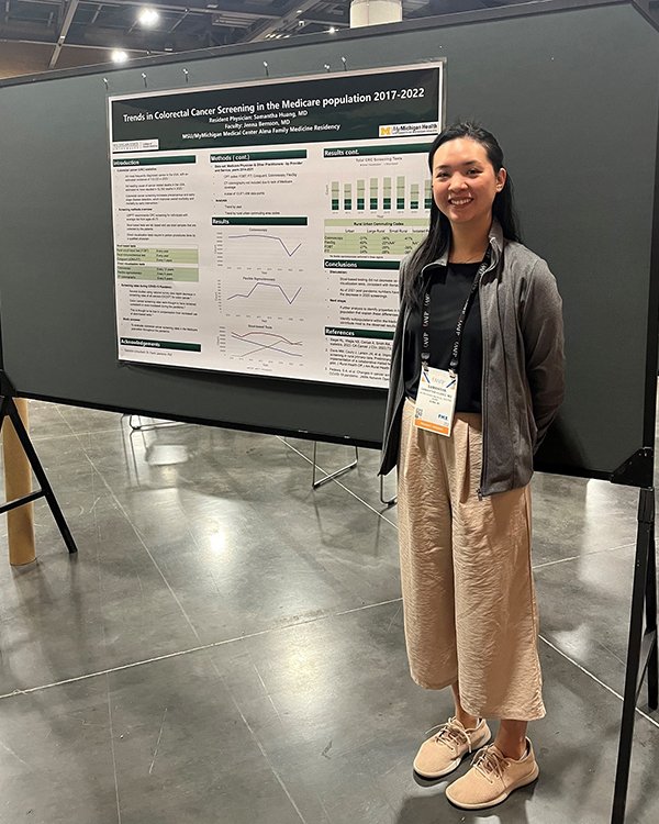 Photo of resident standing in front of a research poster.