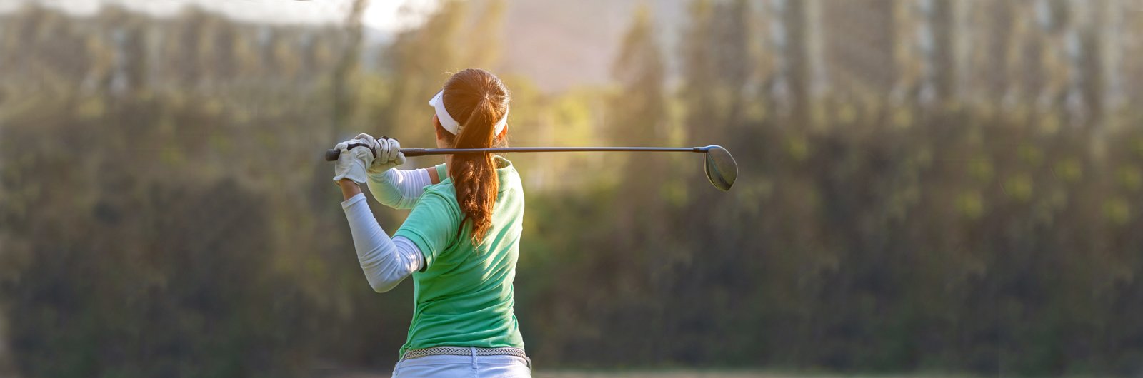 Photo of a woman swinging a golf club.