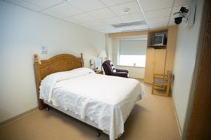 Photo of the Sleep Lab room, includes a bed, televesion and lounge chair.