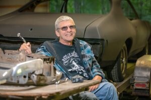 Photo of Richard Konsdorf sitting in his shop enjoying life and feeling stronger, confident and motivated to continue improving.