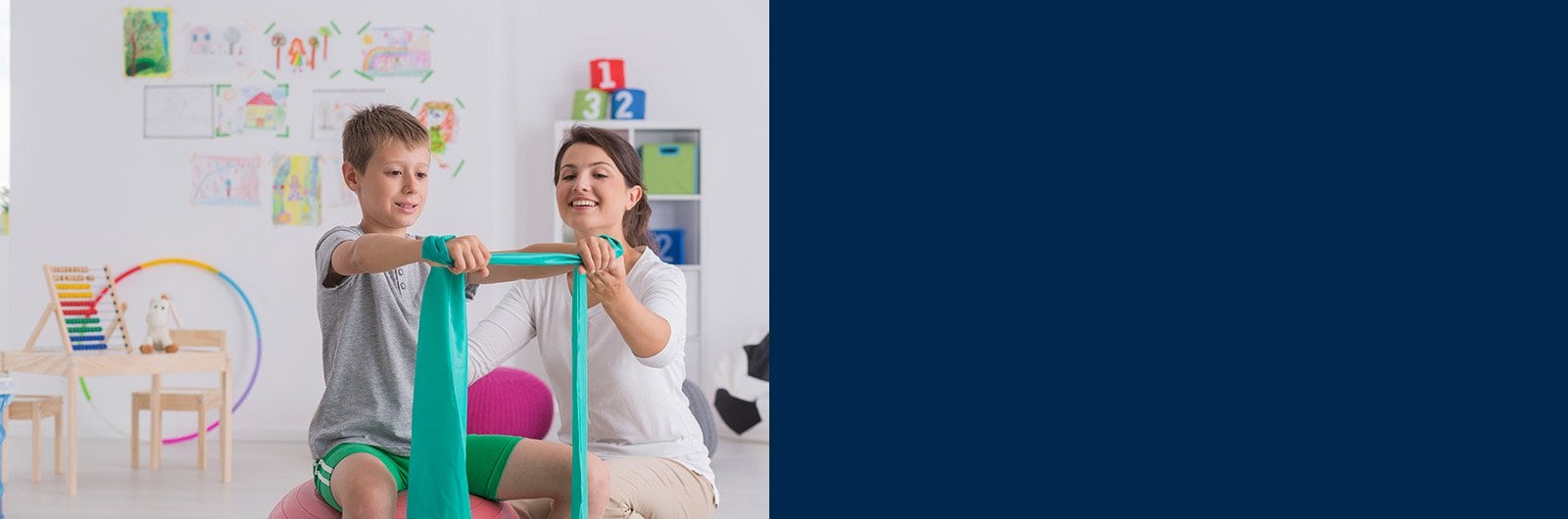 Photo Physical Therapist working with a young boy on strength training.