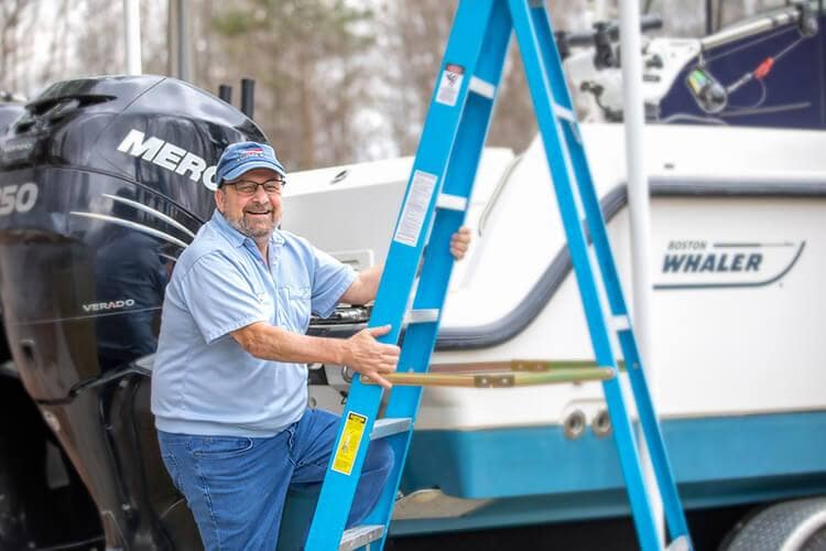 Photo of Larry Crowley climbing a ladder to get into his boat.