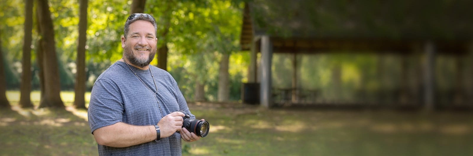 Photo of Jay McDowell sanding in a park taking pictures with his camera.