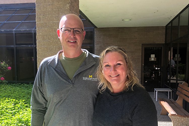 Photo of Steve and Dana Hand, standing outside smiling with the sunshine behind them.