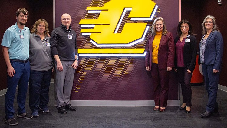 Photo of CMU Athletics and MyMichigan Health staff with flying C CMU logo announcing Sports Medicine partnership.