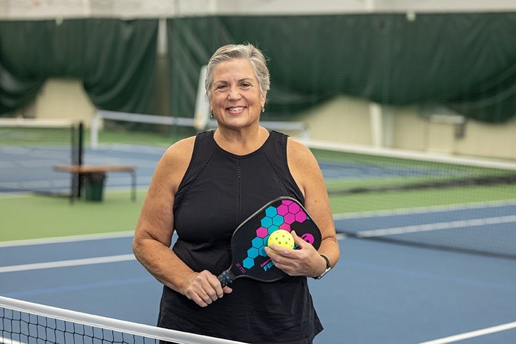 Photo of Kendall Morris standing in front of a Pickleball Court.