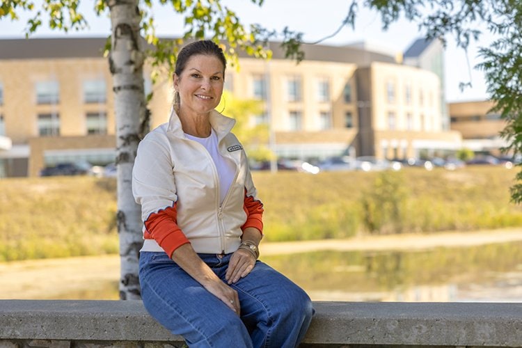 Photo of Michelle Nensewitz sitting on a bench, with the medical center behind her.