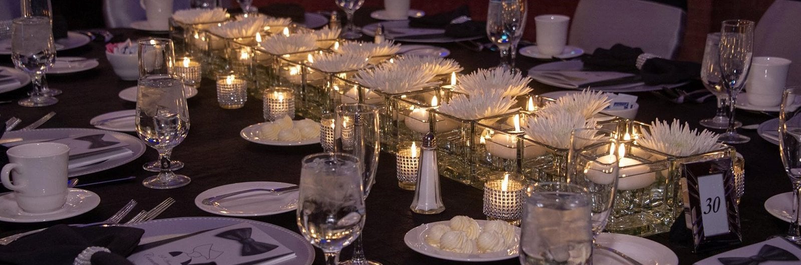 Photo of candles and table settings on a table.