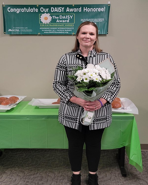 Photo of nurse Margaret Clark holding Daisy award and flowers. 