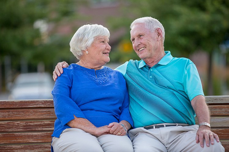 Photo of a senior couple sitting on a park bench enjoying each other's company.