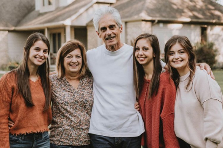 Photo of Mary Montini, her husband, and three daughters standing outside home.