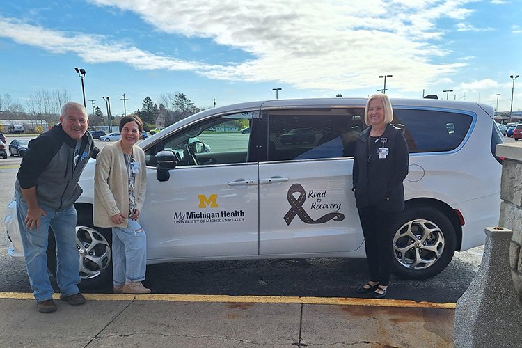 Three staff members of MyMichigan Medical Center Sault stand by new white van.