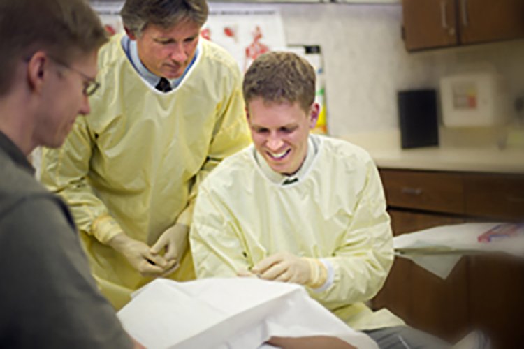 Photo of a faculty physician supporting a resident physician during a procedure.