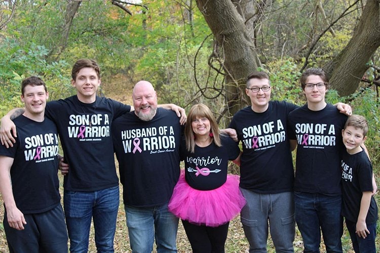 Debbie Maurer and her family wearing pink ribbon shirts, standing outdoors with their arms linked.