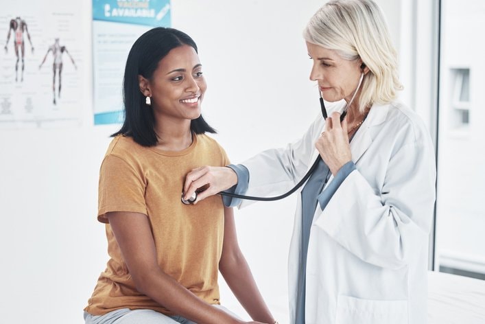 Doctor listening to patients heart during her annual wellness exam.