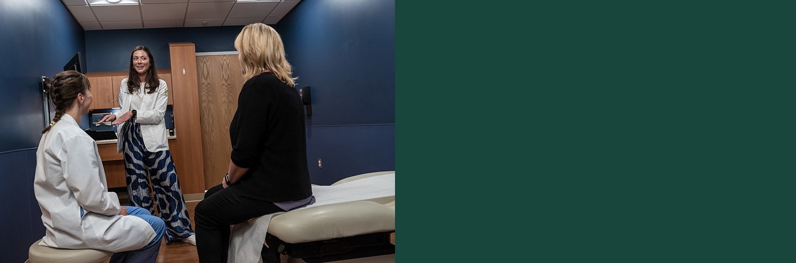 Photo of Eneka Lamb talking with a patient in an exam room.